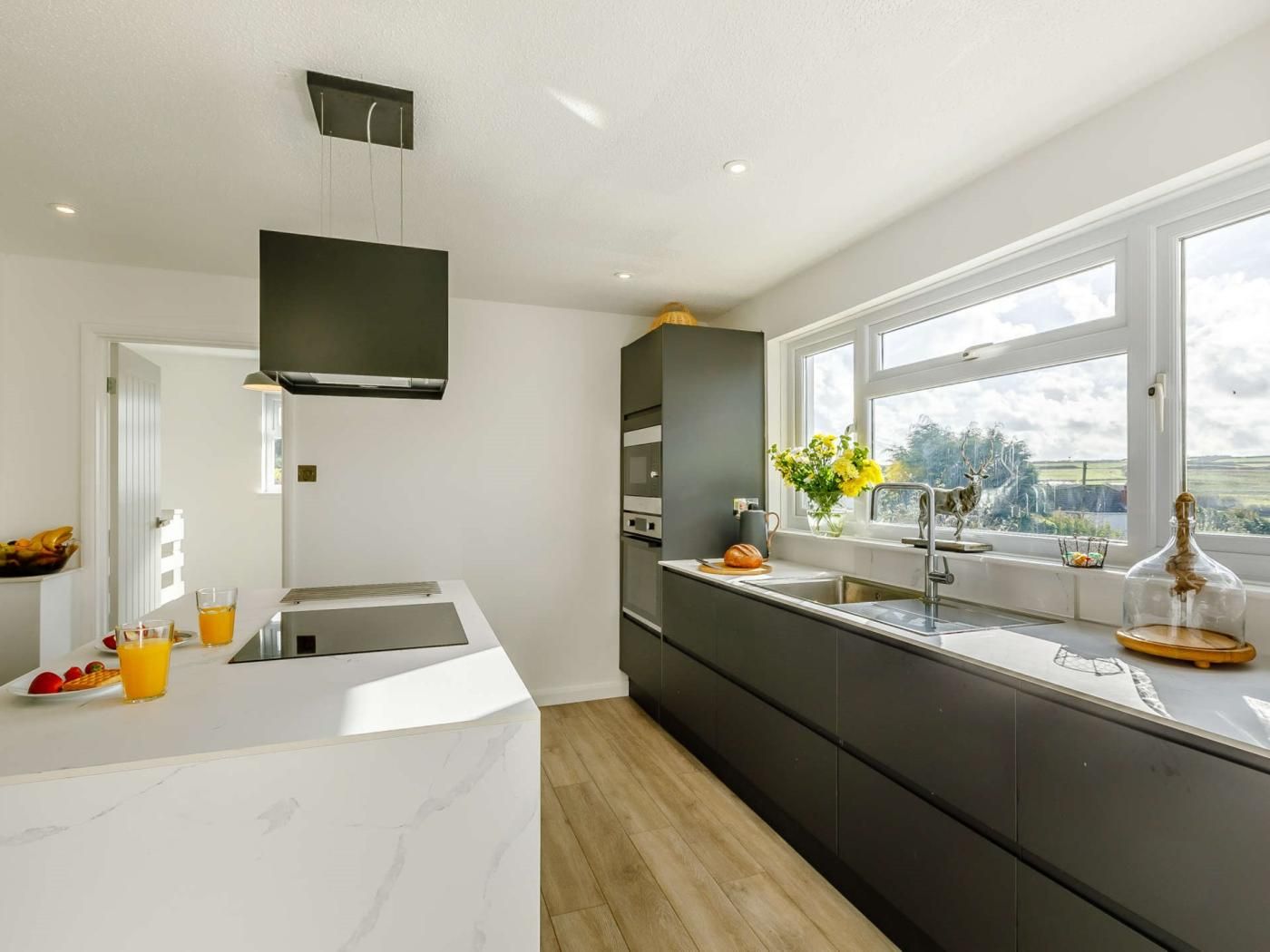 A modern kitchen with a large island, built-in appliances, and a window with a view.