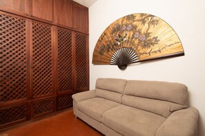 A beige sofa, a wooden lattice partition, and a wall-mounted fan with a floral design. - Santa Croce Living Apartment (Florence)