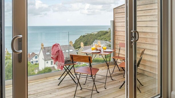 A balcony with a table set for breakfast, overlooking a coastal view. - 2 Bed in Cardigan (oc-89315) (Tresaith)