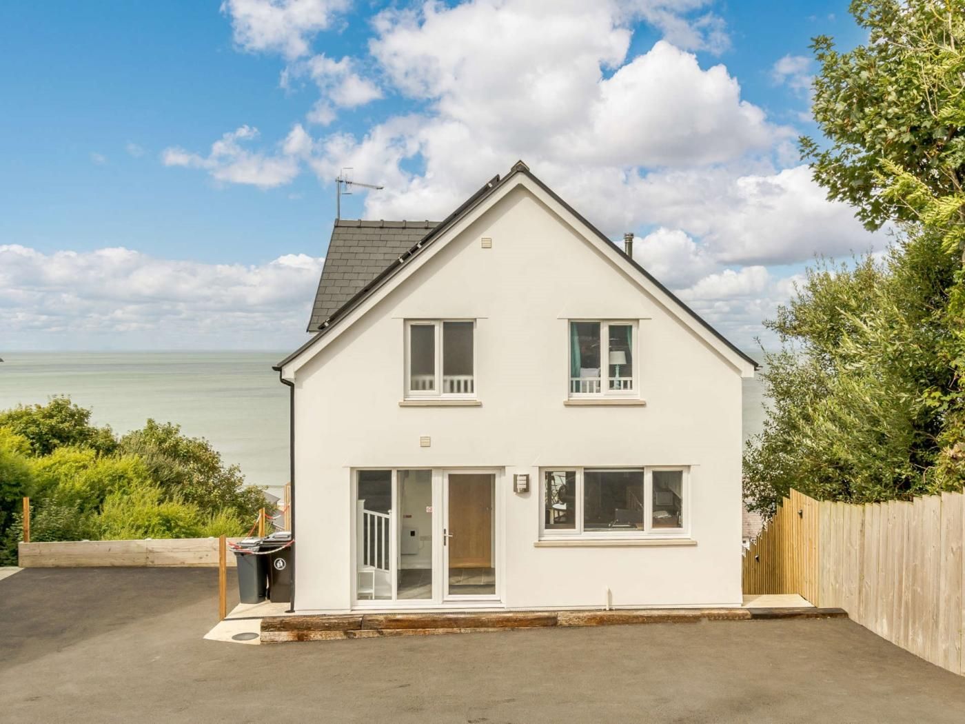 A two-story house with a balcony, a garage, and a view of the sea.