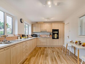 Eine moderne Küche mit Holzausstattung, einer Spüle, einer Mikrowelle, einem Herd und einem Essbereich mit Tisch und Stühlen.