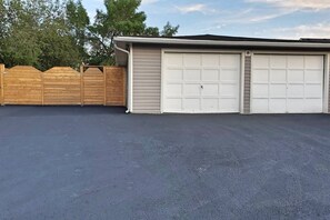 Eine Garage mit zwei weißen Türen und einem Holzzaun im Hintergrund.