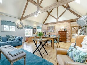 A spacious living area with a high ceiling, wooden beams, a dining table with chairs, a sofa, and a leather armchair. - 2 Bed in Ashbourne (oc-89339) (Ednaston)