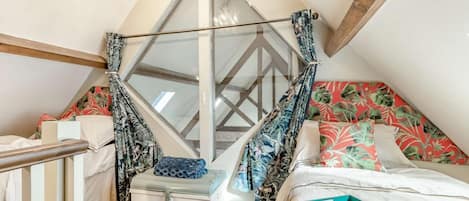 Un dormitorio con cama, una maleta, una bandeja con tazas y platillos, y un sillón colgante.
