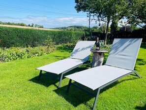 Two white lounge chairs with metal frames, positioned on a grassy lawn with a hedge and a tree in the background. - 2 Bed in Ashbourne (oc-89339) (Ednaston)