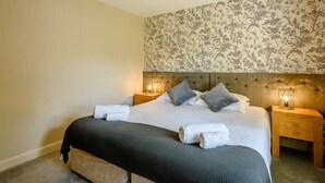 Una camera da letto con un letto, due comodini, una testiera e un lampadario.