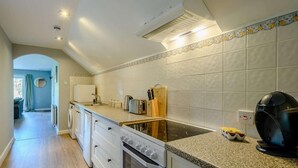 Una cucina con mobili bianchi, un fornello, un lavandino e una macchina da caffè.