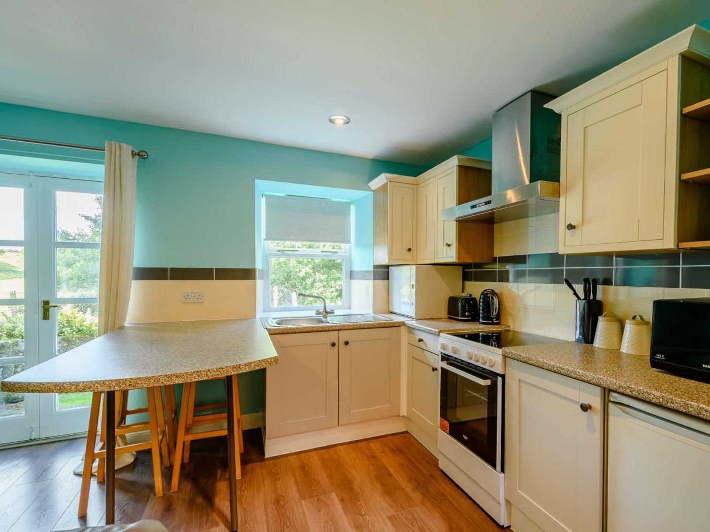 A kitchen with a granite countertop, white cabinets, a double oven, and a window with a view.