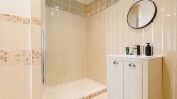 A modern bathroom with a glass-enclosed shower, a vanity with a mirror, and a tiled floor.