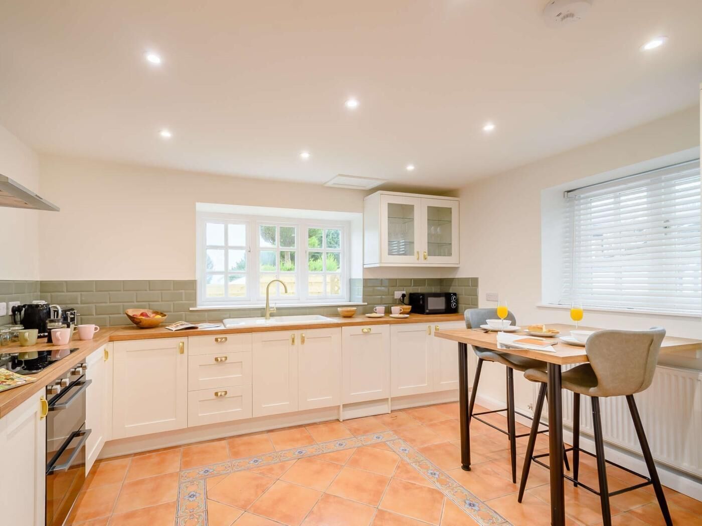 A modern kitchen with a window, a sink, a microwave, and a dining area with a table and chairs.