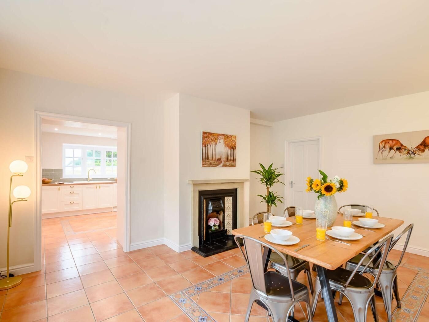 A dining area with a table set for four, a fireplace, and artwork on the walls.