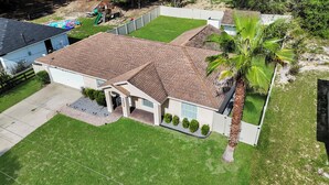 Une maison à deux étages avec un toit en briques, un porche à l’avant et une pelouse bien entretenue.