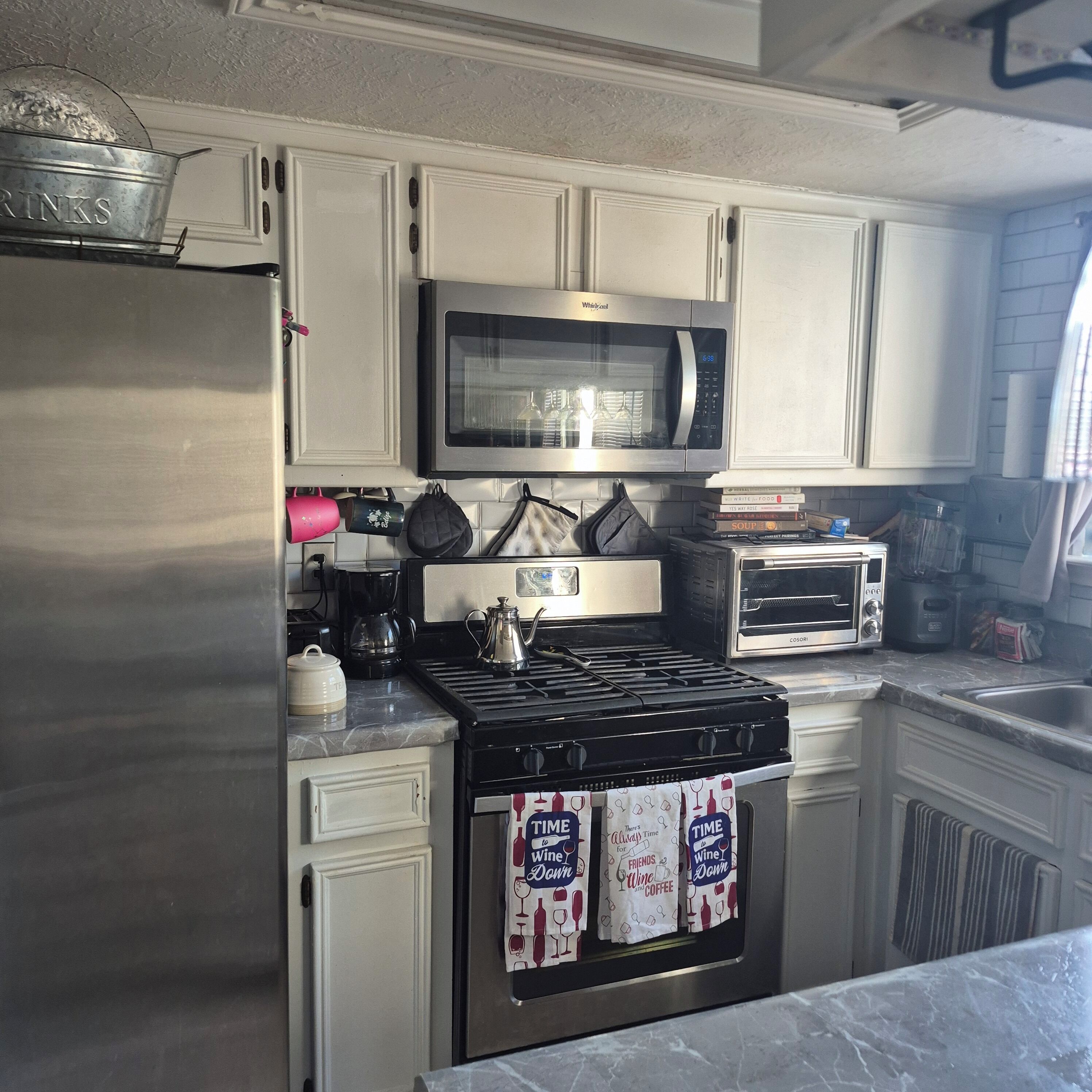 A kitchen with a stainless steel refrigerator, a microwave, a toaster oven, and a stove.