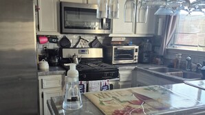 A kitchen with a stainless steel refrigerator, a microwave, a toaster oven, and a sink.