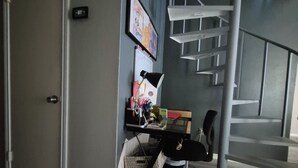A modern office space with a desk, chair, and a staircase.