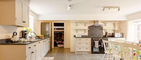 Una cucina moderna con forno a incasso, un'area pranzo con tavolo e sedie, e vista su un soggiorno con camino.