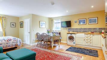 A compact living space with a bed, a dining area, a kitchen, and a washing machine.