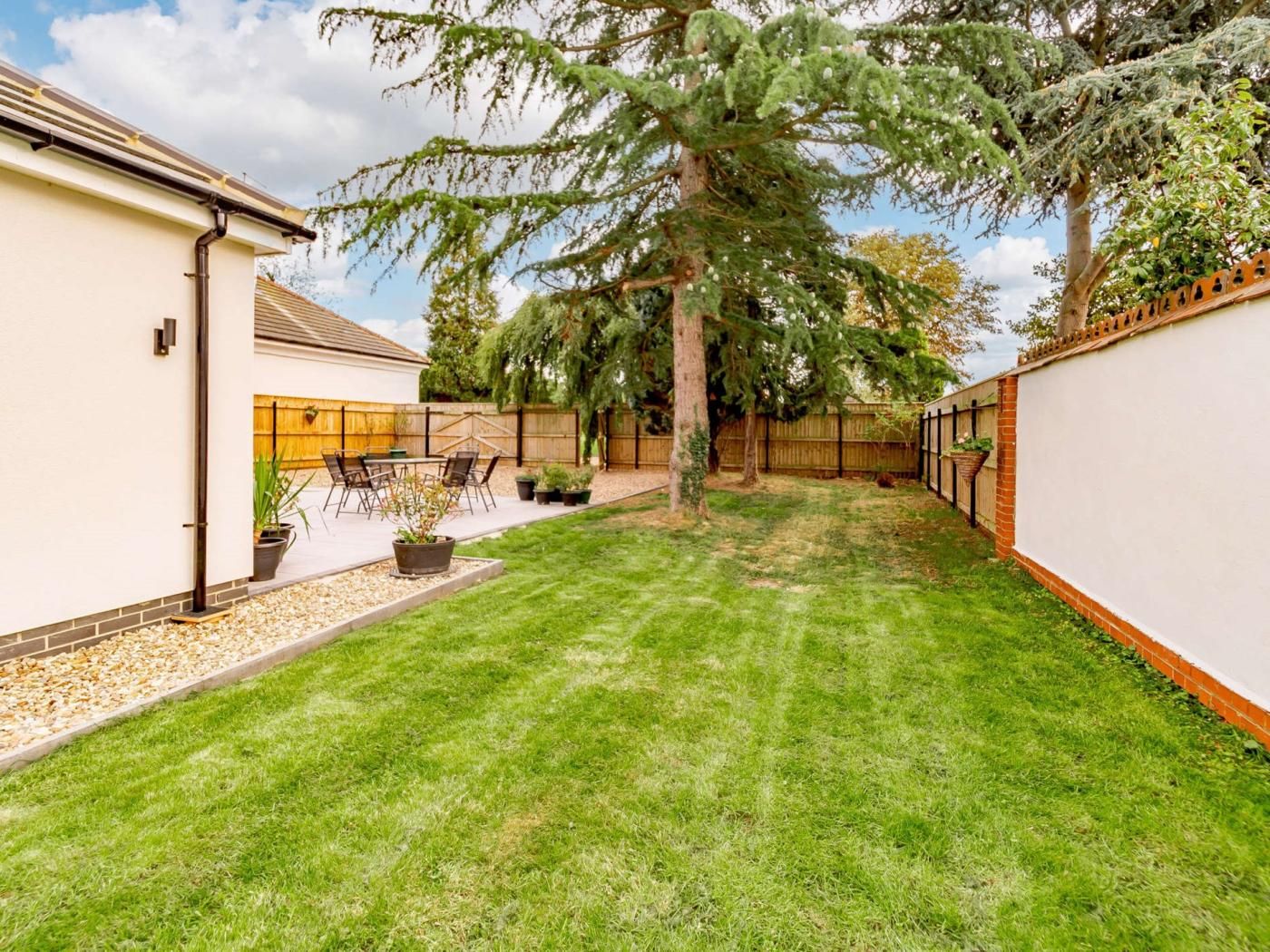 A backyard with a lawn, a wooden table with chairs, and a potted plant.