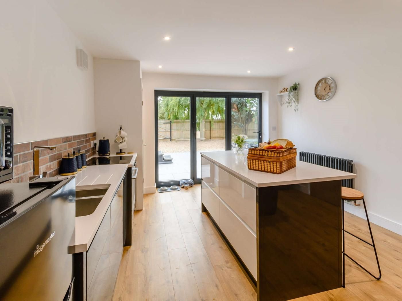 Une cuisine moderne dotée d’un four encastré, d’un coin repas avec une table et d’une vue sur l’extérieur grâce à une porte vitrée.