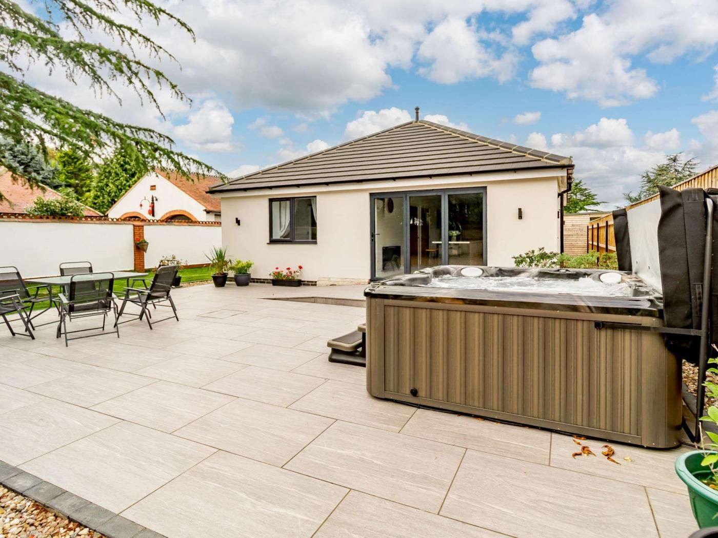 Une propriété résidentielle dotée d’un patio, d’un jacuzzi et d’un ensemble de mobilier de jardin pour les repas.