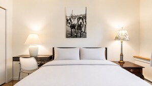 A hotel room with a bed, two bedside tables, a desk, a chair, and a lamp. - Pool, Hot Tub, Spa & Ski Shuttle (Killington)