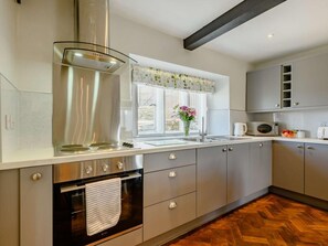 Eine moderne Küche mit Dunstabzugshaube aus Edelstahl, einem eingebauten Backofen und einem Fenster mit Ausblick.