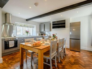 A modern kitchen with a wooden dining table, stainless steel appliances, and a herringbone floor pattern. - 3 Bed in Penrith (oc-89068) (Tirril)