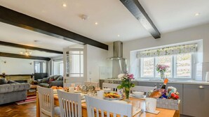 Une cuisine moderne avec une table à manger dressée pour le repas, un coin salon avec un canapé et une cheminée.