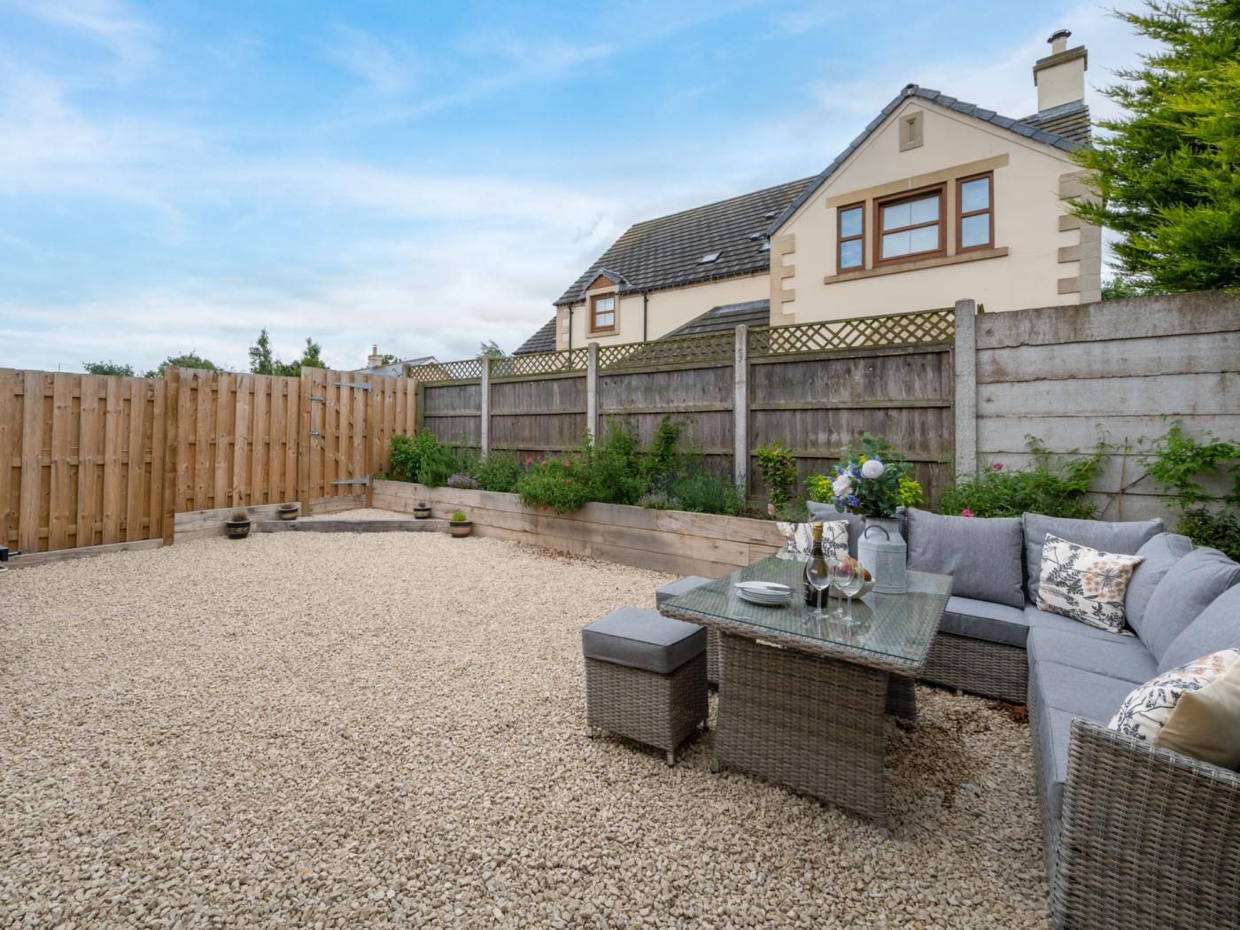 Une terrasse avec des meubles d’extérieur, une clôture en bois et une maison en arrière-plan.