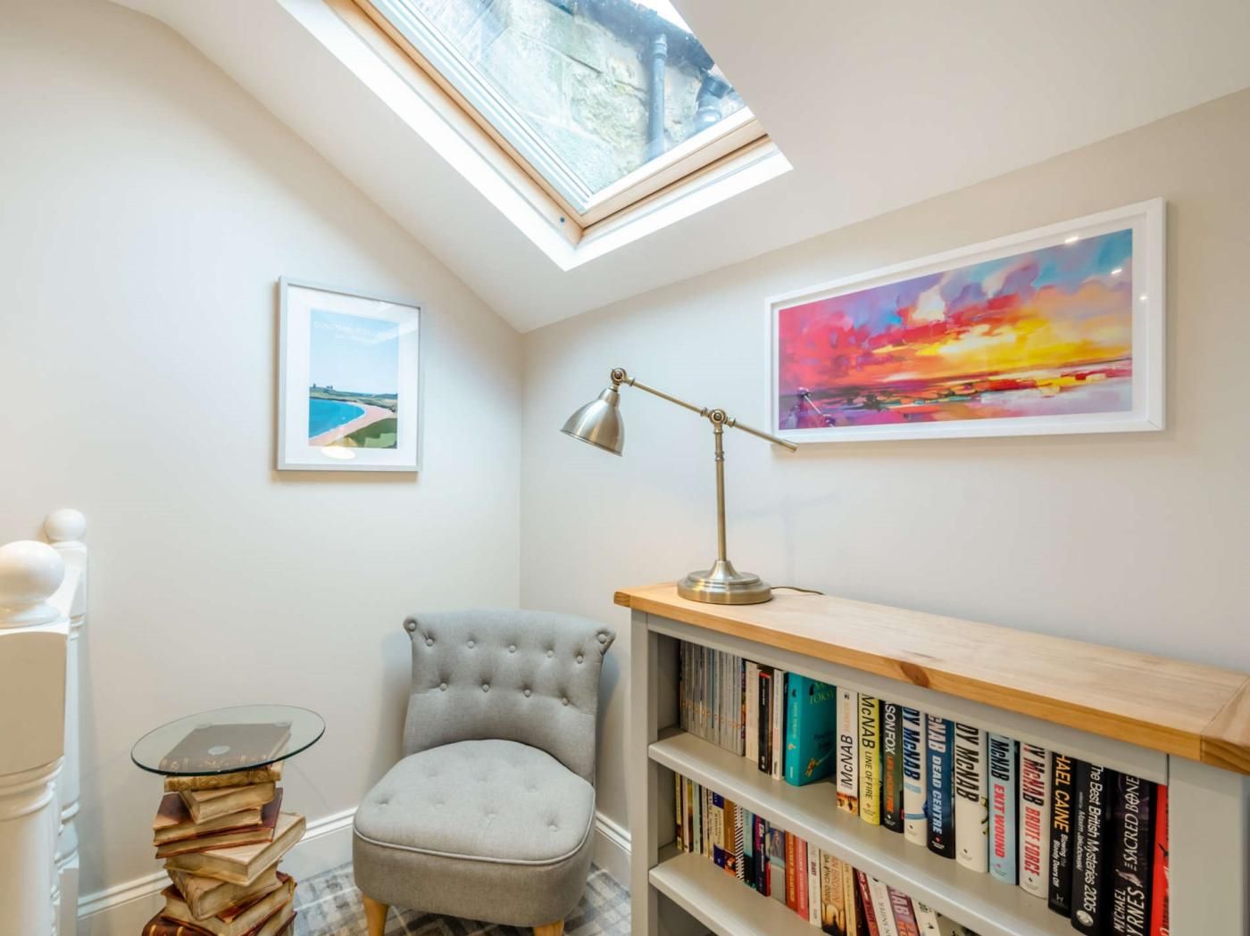 Un coin lecture avec un fauteuil confortable, un bureau avec une lampe et une bibliothèque remplie de livres.