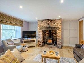 A living room with a brick fireplace, a television, and seating arrangements. - 3 Bed in Berwick-upon-tweed (oc-89814) (Lowick)