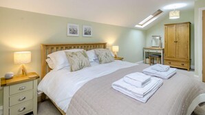 Une chambre à coucher comprenant un lit, des lampes de chevet, un bureau, un miroir et une armoire.
