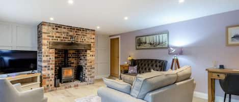 A living room with a brick fireplace, a sofa, a television, and a desk.