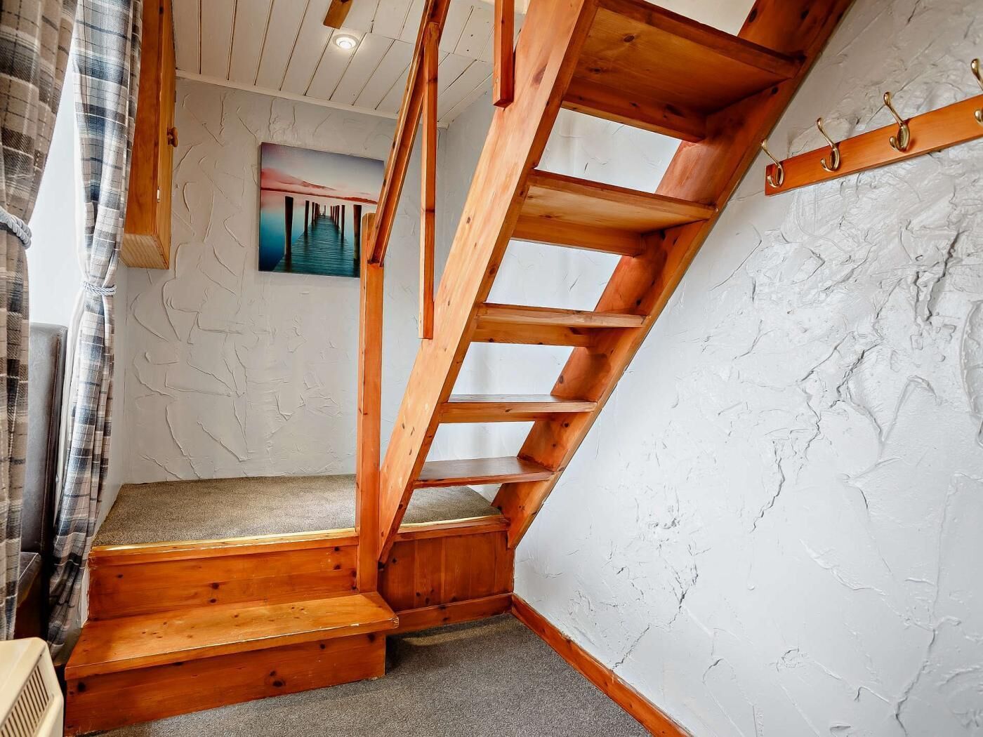 Eine Holztreppe führt zu einem Schlafbereich mit Blick ins Freie.