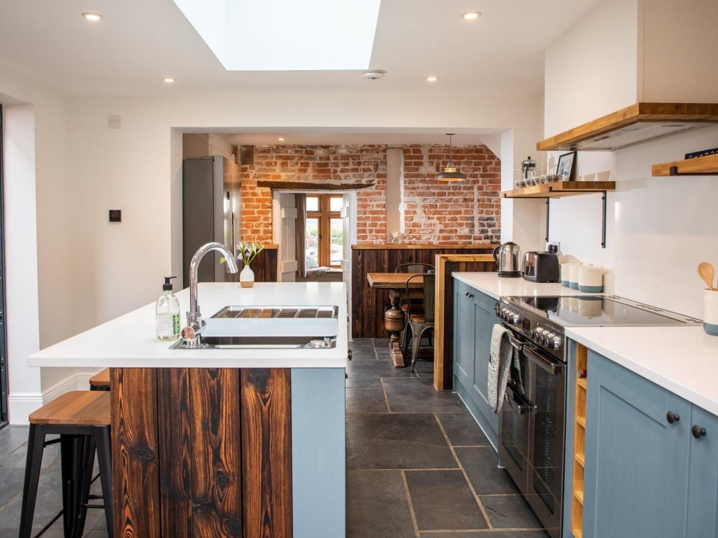 A modern kitchen with a central island, a built-in oven, and a brick wall.
