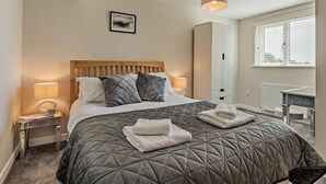 A bedroom with a bed, bedside lamps, a wardrobe, a radiator, and a window with blinds. - 2 Bed in Grange-over-sands (oc-89206) (Cartmel)