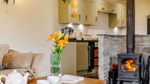 Ein gemütliches Wohnzimmer mit Kamin, einer Couch, einem Couchtisch mit Teetassen und einer Blumenvase.