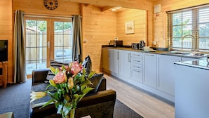 Un intérieur en bois comprenant une cuisine, un coin repas et une horloge au mur.