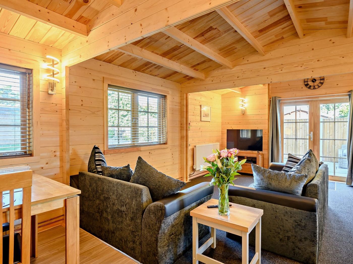 L'intérieur d'un chalet en bois chaleureux et accueillant, avec un canapé, une table à manger et un téléviseur.