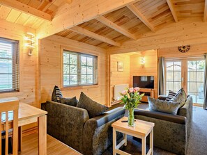A cozy wooden cabin interior with a sofa, a dining table, and a television. - 2 Bed in Saxmundham (oc-89929) (Snape)