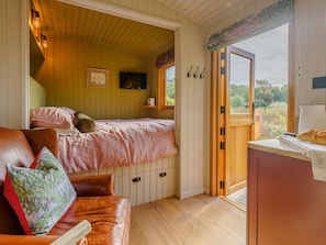 A cozy bedroom with a bed, a wooden ceiling, a television, and a window with a view of greenery. - 1 Bed in Sandown (oc-89932) (Newchurch)