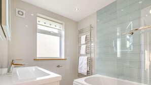 Ein modernes Badezimmer mit Badewanne, Waschbecken und einer Duschkabine aus Glas.