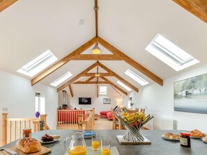 A high-ceilinged room with skylights, a dining area with breakfast items, and a cozy seating area. - 3 Bed in Newquay (oc-89943) (Tregurrian)