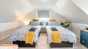A bedroom with two beds, a small table, a plant, and a window. - 3 Bed in Bideford (oc-89991) (Appledore)