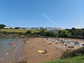 A beach with people, kayaks, and tents. Houses are visible in the background. - 3 Bed in Llandysul (oc-90019) (Llandysiliogogo)
