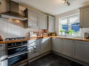 Eine moderne Küche mit Gasherd, Backofen und weißen Schränken.