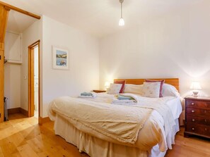 Ein Schlafzimmer mit einem hölzernen Bett, einem Nachttisch, einer Lampe und einer Tür zu einem weiteren Raum.