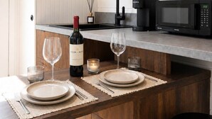 A modern kitchen with a wooden countertop, a built-in microwave, and a wine bottle.