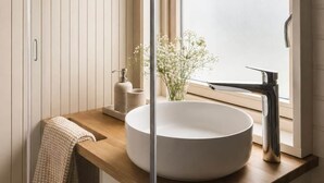 A modern bathroom with a round sink, a large arched window, and a wooden countertop.