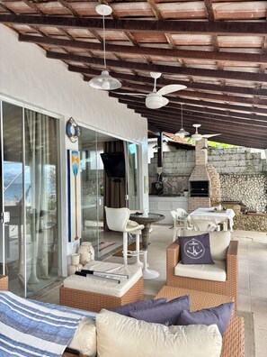 Un espace extérieur aménagé avec des meubles en osier, un barbecue et une vue sur la mer.